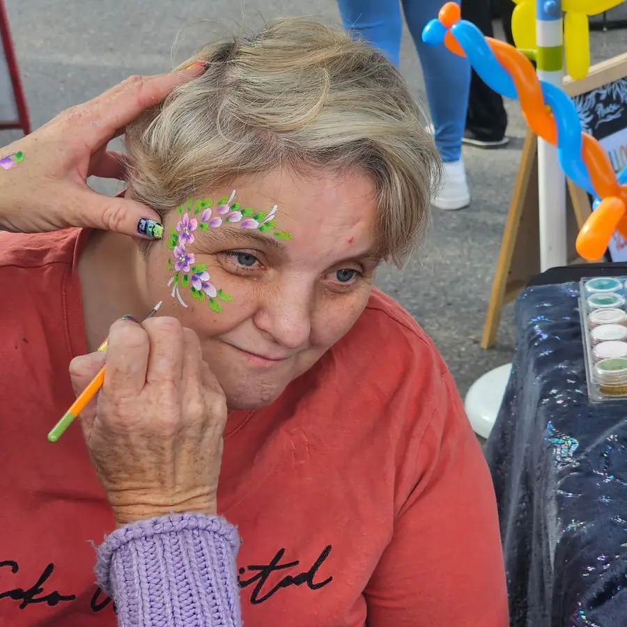 An NDIS participant having her face painted at a community festival in South Australia